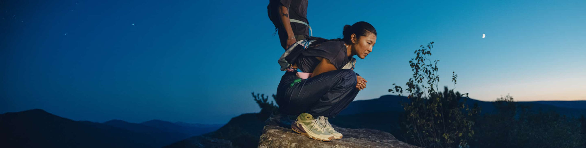 Person pausiert auf Felsen bei Dämmerung und trägt wasserdichte KEEN Targhee Apex Mid Wanderschuhe.
