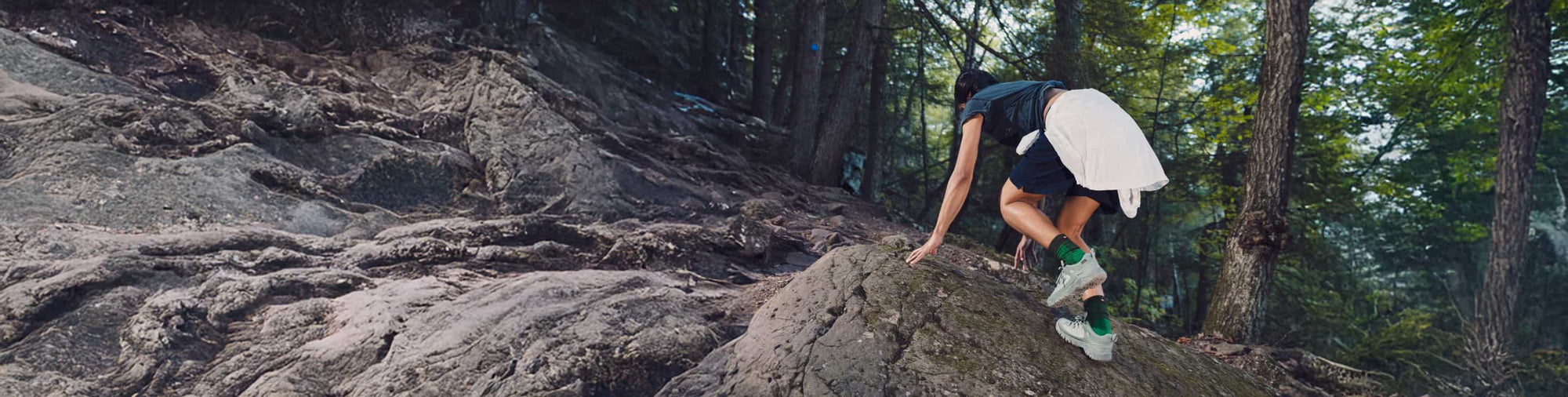Person klettert über felsigen Waldpfad und trägt robuste KEEN Targhee Wanderschuhe für anspruchsvolles Gelände.