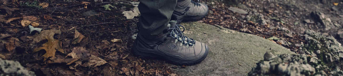 Person steigt über felsigen Waldpfad und trägt wasserdichte KEEN Targhee IV Mid Wanderschuhe im Gelände.