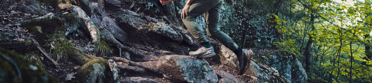 Braune Wanderstiefel auf mit Moos bewachsenem Felsen.