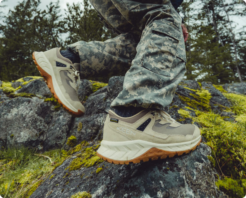 KEEN Hightrail wasserdichte Wanderschuhe in beige-grau mit brauner Sohle auf moosigen Steinen 