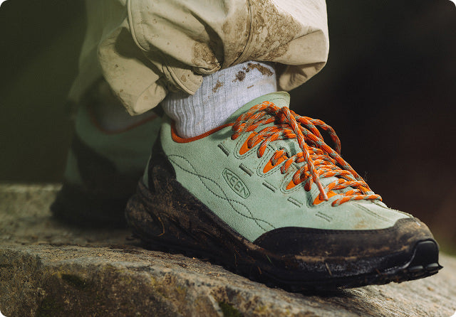 KEEN Jasper Zionic Sneaker mint-grün mit orangenen Schnürsenkeln auf Felsen
