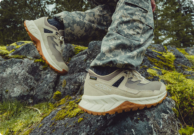 KEEN Hightrail wasserdichte Wanderschuhe in beige-grau mit brauner Sohle auf moosigen Steinen 