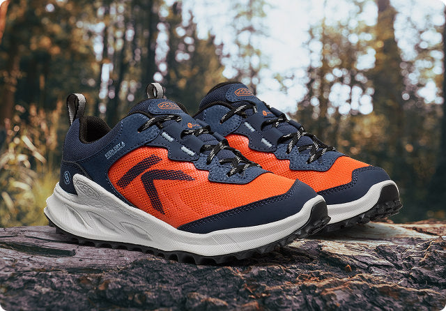 KEEN wasserdichte Kinder-Wanderschuhe in orange-blau auf Baumstamm im Herbstwald