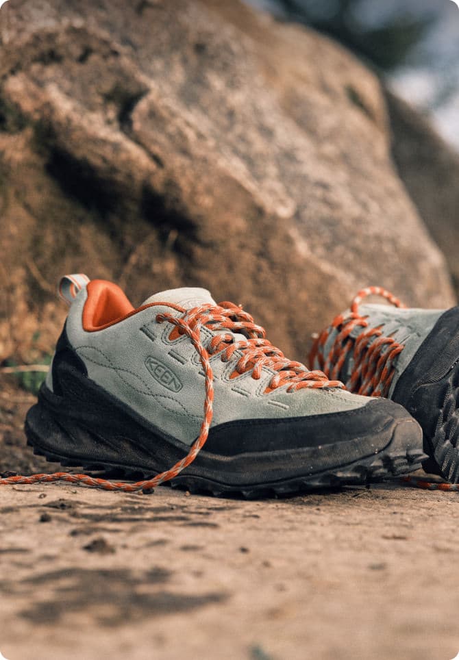 Keen Sneaker grau-orange mit Kletterseil auf Felsen - robuste Approach-Sneaker für Outdoor-Aktivitäten