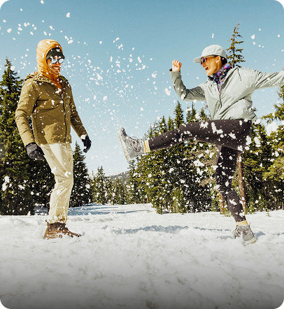 Zwei Personen spielen im Schnee und tragen KEEN Winterstiefel bei sonnigem Winterwetter.