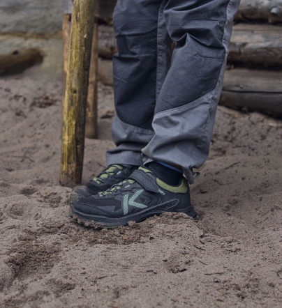 Schwarzer KEEN Kinder-Outdoorschuh mit robustem Profil im Sand.