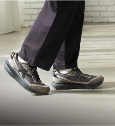 Dunkle KEEN Herren-Walking-Sneaker beim Gehen auf hellem Boden.