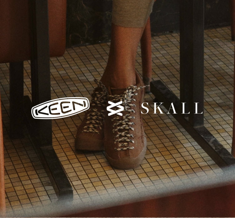 KEEN x SKALL braune Outdoor-Schuhe mit markanten Schnürsenkeln auf retro gelbem Fliesenboden