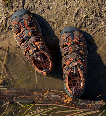 Ein Paar braune Arroyo-Sandalen im Sand