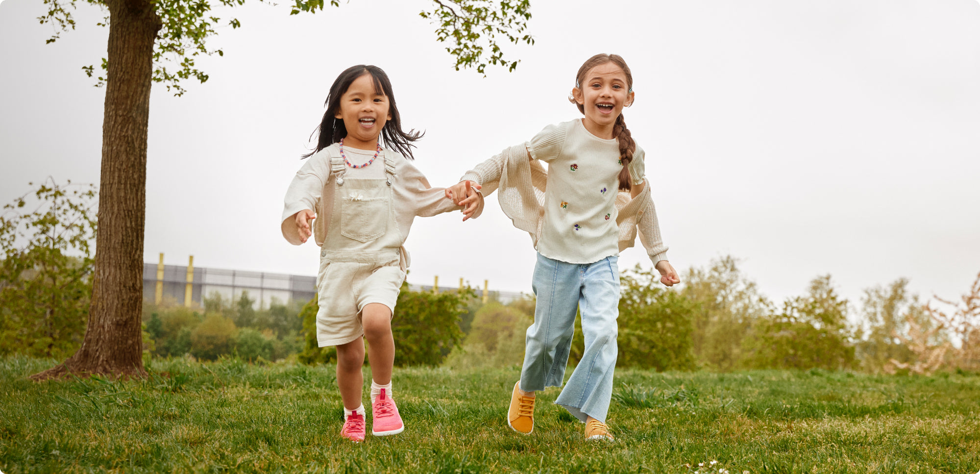 Kinder tragen KNX-Schuhe, halten sich an den Händen und rennen in der Natur.