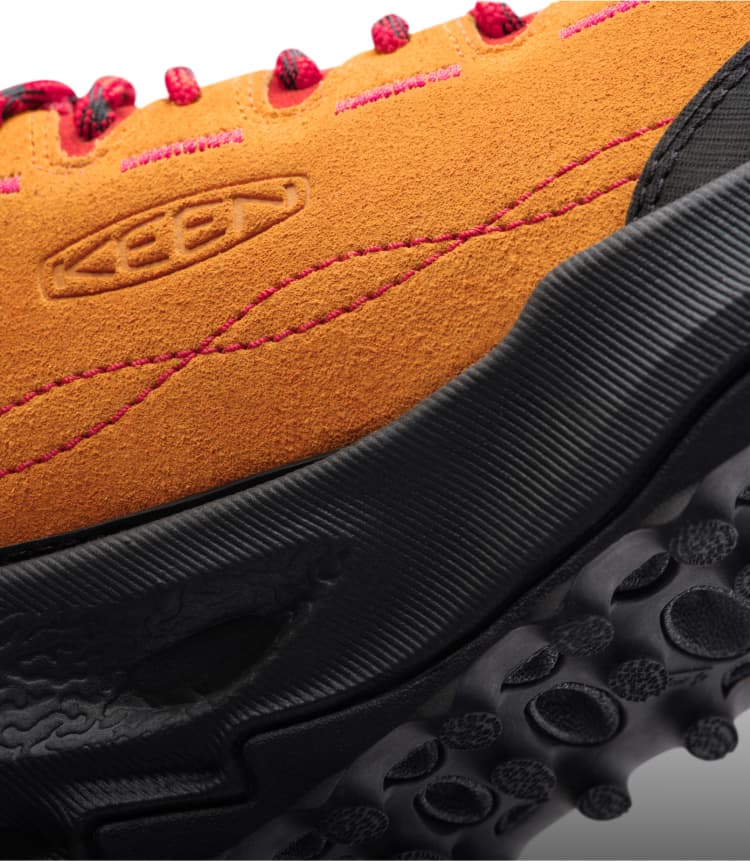 Nachansicht der Außenseite eines orangen Veloursledersneakers mit KEEN Logo, roten Schnürsenkeln, roten Nähten und schwarzer Außensohle.