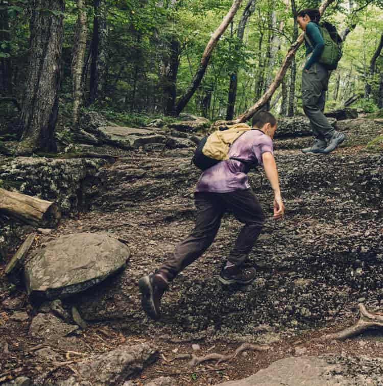 Person steigt über felsigen Waldpfad und trägt wasserdichte KEEN Targhee IV Mid Wanderschuhe im Gelände.
