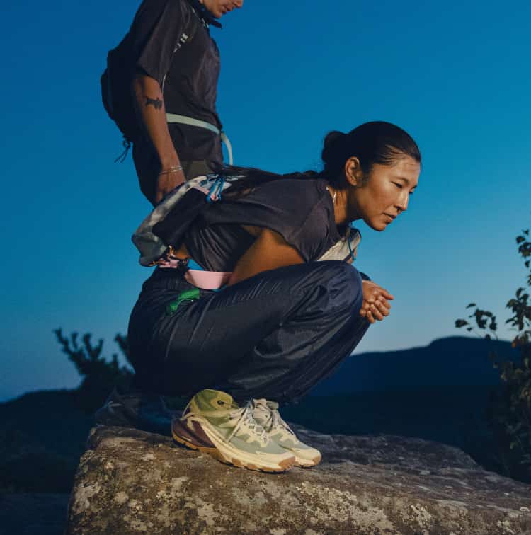 Person pausiert auf Felsen bei Dämmerung und trägt wasserdichte KEEN Targhee Apex Mid Wanderschuhe.